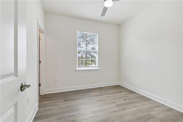 empty room with ceiling fan, light wood-style flooring, and baseboards