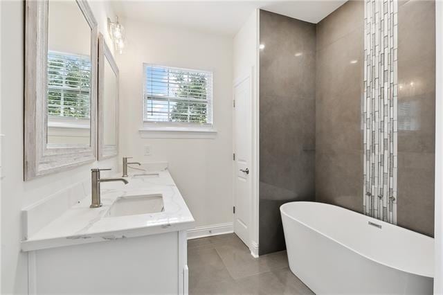 full bathroom with baseboards, a freestanding bath, a sink, and double vanity