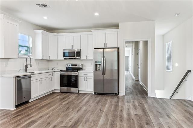 kitchen with stainless steel appliances, visible vents, light wood-style floors, white cabinets, and light countertops