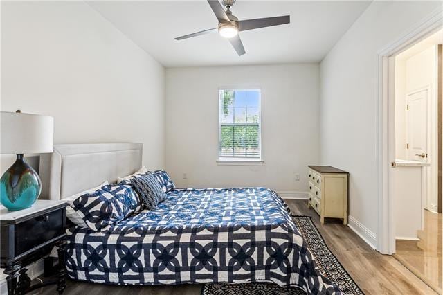 bedroom with ceiling fan, wood finished floors, connected bathroom, and baseboards