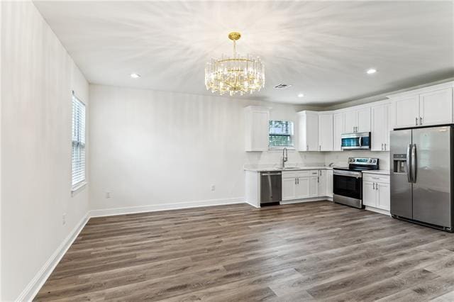 kitchen featuring appliances with stainless steel finishes, white cabinetry, dark wood finished floors, and baseboards