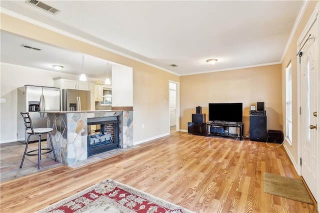 living room with light hardwood / wood-style flooring, crown molding, and a stone fireplace