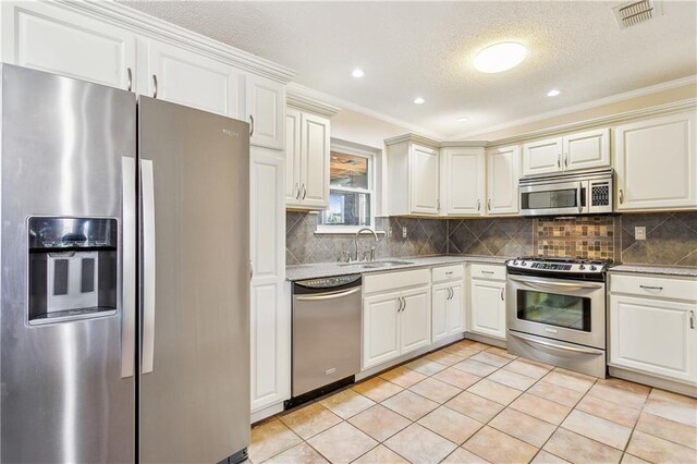 kitchen featuring light tile patterned floors, stainless steel appliances, decorative backsplash, crown molding, and sink