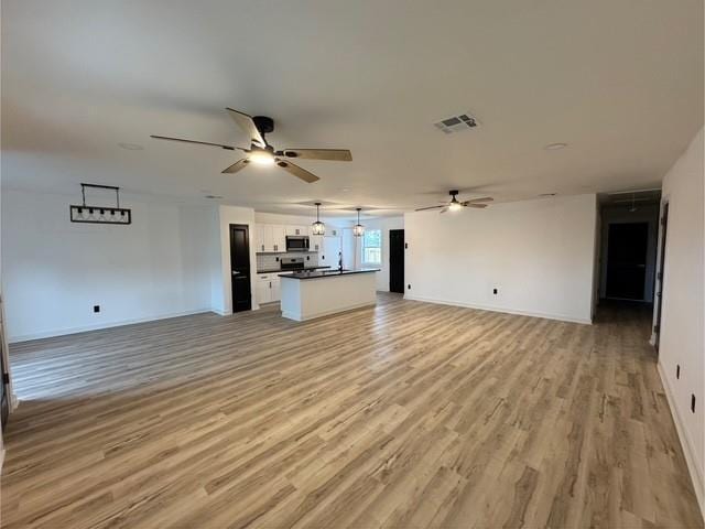 unfurnished living room featuring ceiling fan and light hardwood / wood-style floors