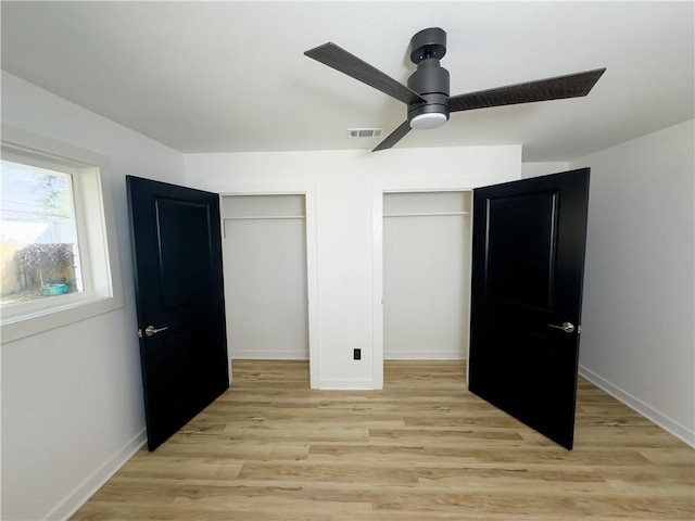 unfurnished bedroom with two closets, ceiling fan, and light wood-type flooring