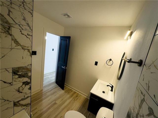 bathroom with wood-type flooring, toilet, vanity, and a shower