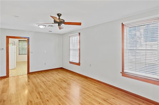 spare room with ceiling fan, light wood-type flooring, and plenty of natural light