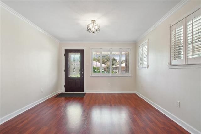 entrance foyer with a wealth of natural light, ornamental molding, and dark hardwood / wood-style flooring