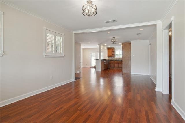 unfurnished living room with an inviting chandelier, dark hardwood / wood-style floors, and crown molding