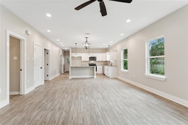 unfurnished living room featuring ceiling fan with notable chandelier, light hardwood / wood-style flooring, and sink