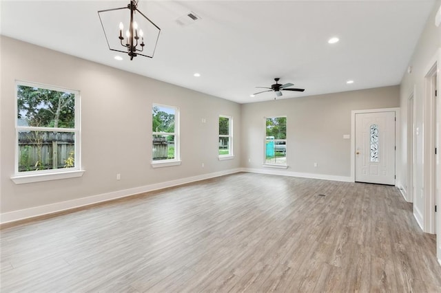 unfurnished living room featuring light hardwood / wood-style floors, plenty of natural light, and ceiling fan with notable chandelier