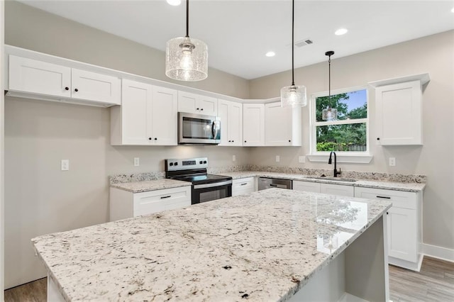 kitchen featuring white cabinets, appliances with stainless steel finishes, and pendant lighting