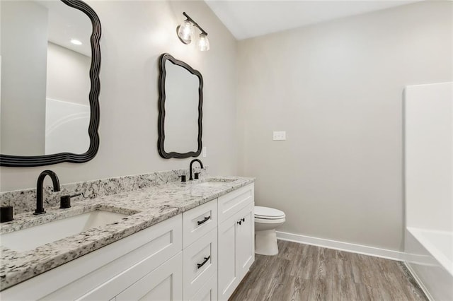 bathroom with toilet, a tub to relax in, hardwood / wood-style floors, and vanity