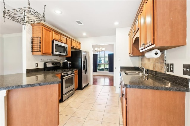 kitchen with light tile patterned floors, kitchen peninsula, stainless steel appliances, a notable chandelier, and sink