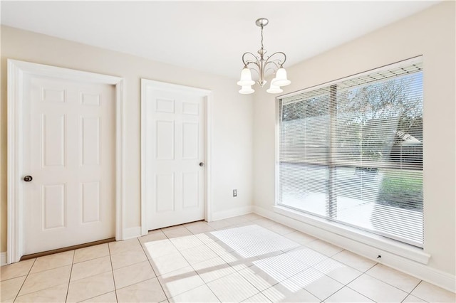 unfurnished dining area with light tile patterned floors, a wealth of natural light, and an inviting chandelier