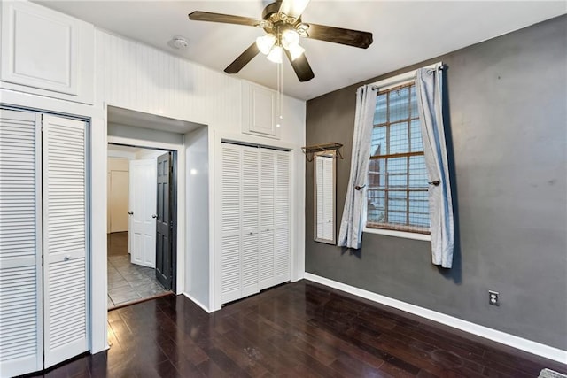 unfurnished bedroom with ceiling fan and dark wood-type flooring