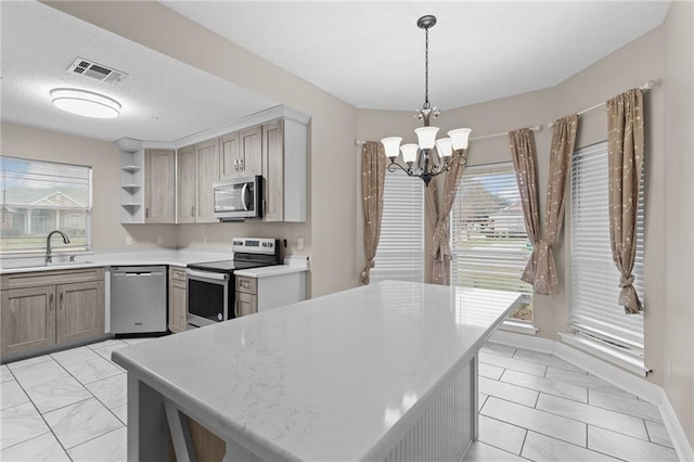 kitchen with appliances with stainless steel finishes, a healthy amount of sunlight, a notable chandelier, decorative light fixtures, and sink