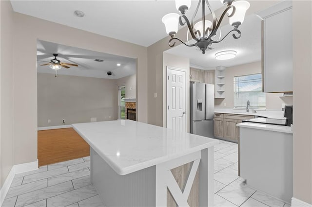 kitchen featuring ceiling fan with notable chandelier, stainless steel refrigerator with ice dispenser, sink, hanging light fixtures, and stove