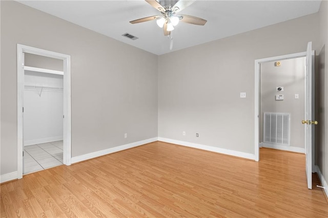 unfurnished bedroom featuring ceiling fan, a closet, a spacious closet, and light hardwood / wood-style flooring