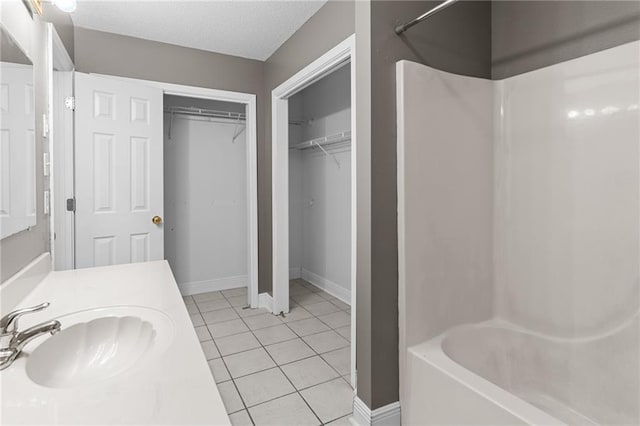 bathroom with vanity, tile patterned flooring, a textured ceiling, and washtub / shower combination