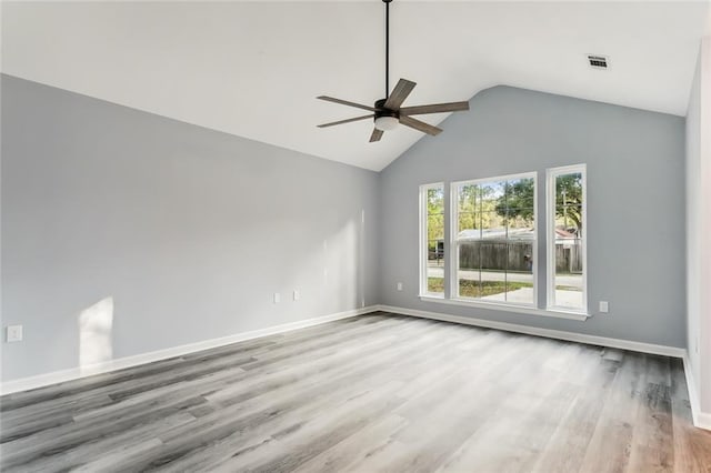 empty room with ceiling fan, lofted ceiling, and light hardwood / wood-style floors