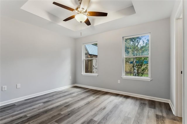 spare room featuring a raised ceiling, dark wood-type flooring, and ceiling fan