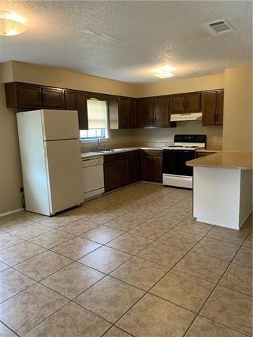 kitchen featuring light tile patterned floors, white appliances, a textured ceiling, and dark brown cabinetry