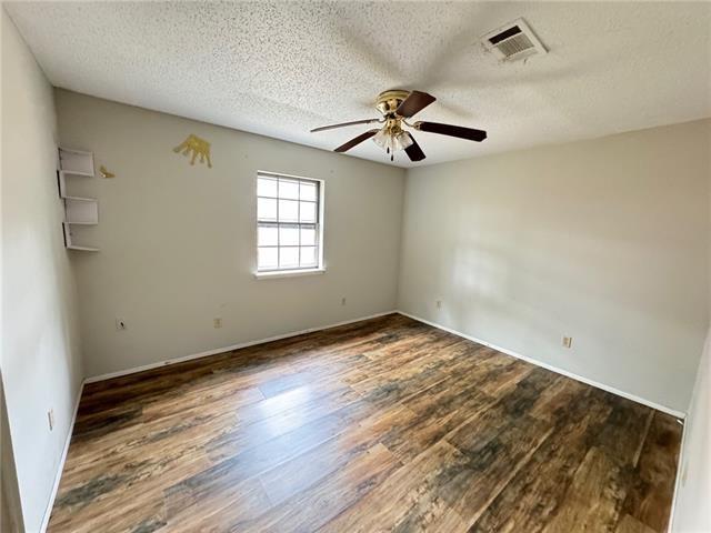 spare room featuring ceiling fan, dark hardwood / wood-style flooring, and a textured ceiling