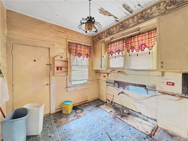 kitchen featuring decorative light fixtures, cream cabinetry, and wooden walls