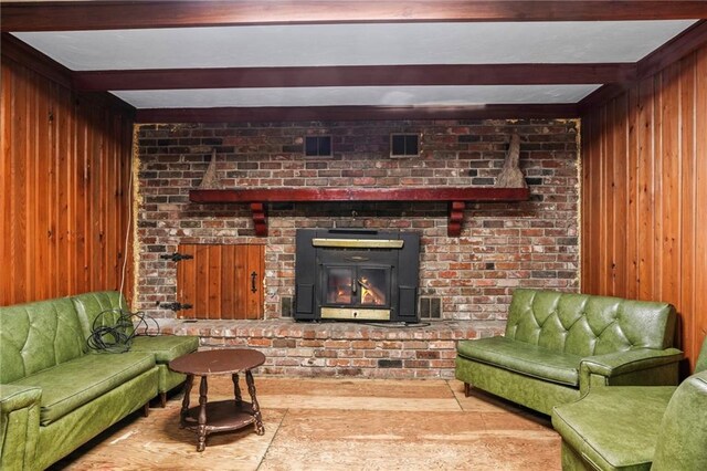 living room featuring beam ceiling, wood walls, and a fireplace