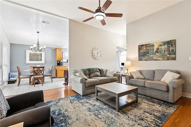 living room with ceiling fan with notable chandelier and light hardwood / wood-style floors