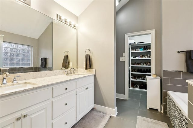 bathroom featuring tile patterned flooring, tiled tub, and vanity