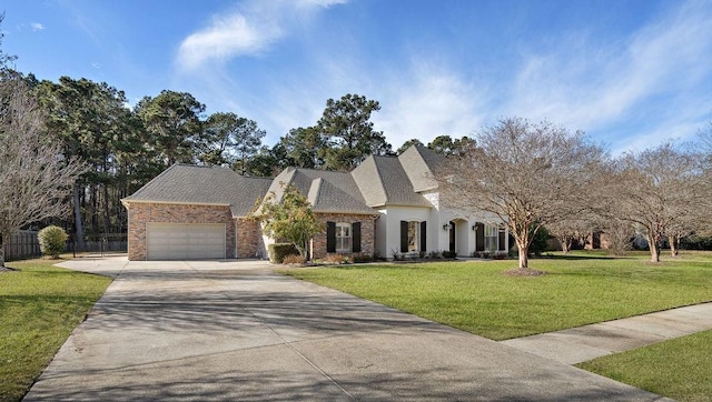 french provincial home featuring a front yard and a garage