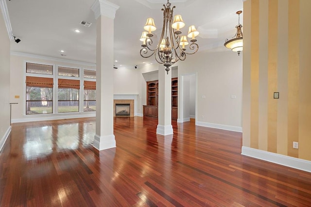 unfurnished living room with ornate columns, dark wood-type flooring, a fireplace, a chandelier, and crown molding