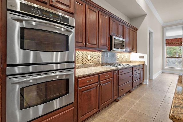 kitchen featuring appliances with stainless steel finishes, decorative backsplash, light tile patterned flooring, ornamental molding, and light stone counters