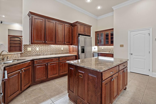 kitchen with light tile patterned floors, a center island, high quality fridge, ornamental molding, and sink