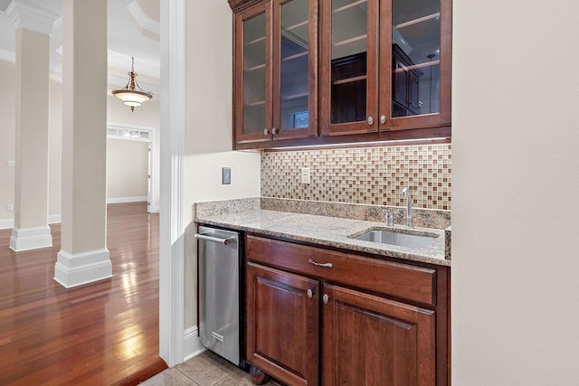 kitchen with tasteful backsplash, sink, hanging light fixtures, ornamental molding, and light stone counters