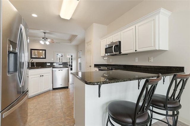 kitchen with a kitchen bar, kitchen peninsula, white cabinetry, and stainless steel appliances