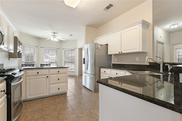 kitchen with white cabinets, stainless steel appliances, sink, kitchen peninsula, and ceiling fan