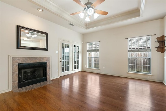 unfurnished living room with a healthy amount of sunlight, a fireplace, and a tray ceiling