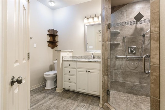 bathroom featuring toilet, a shower with shower door, wood-type flooring, and vanity