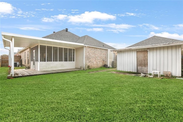 rear view of property featuring central AC unit, a yard, and a sunroom