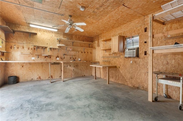 interior space with wooden walls, ceiling fan, concrete floors, cooling unit, and a workshop area