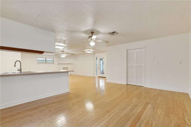 unfurnished living room with ceiling fan, light hardwood / wood-style floors, and sink