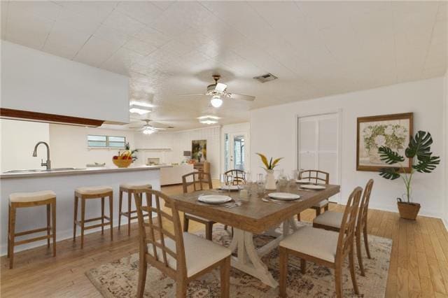 dining area with a wealth of natural light, light hardwood / wood-style floors, and sink