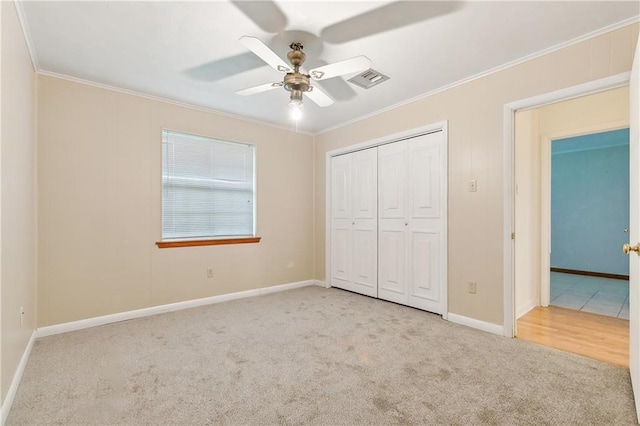 unfurnished bedroom featuring ceiling fan, light colored carpet, a closet, and ornamental molding