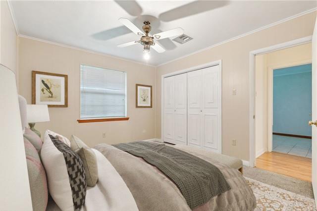 bedroom featuring ceiling fan, a closet, crown molding, and carpet flooring