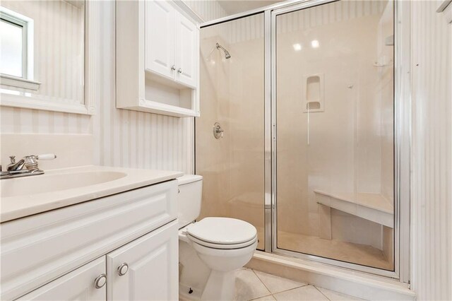 bathroom with a shower with shower door, toilet, vanity, and tile patterned flooring