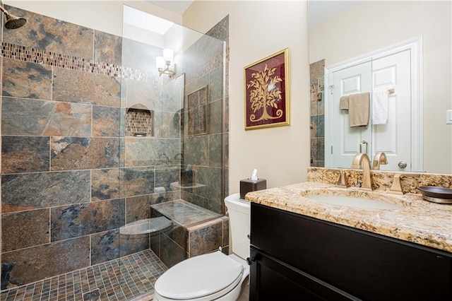 bathroom with toilet, vanity, and tiled shower