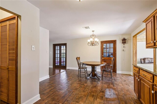 dining room with plenty of natural light, dark hardwood / wood-style floors, a notable chandelier, and french doors